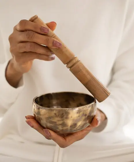 A person holding a bowl and a wooden stick