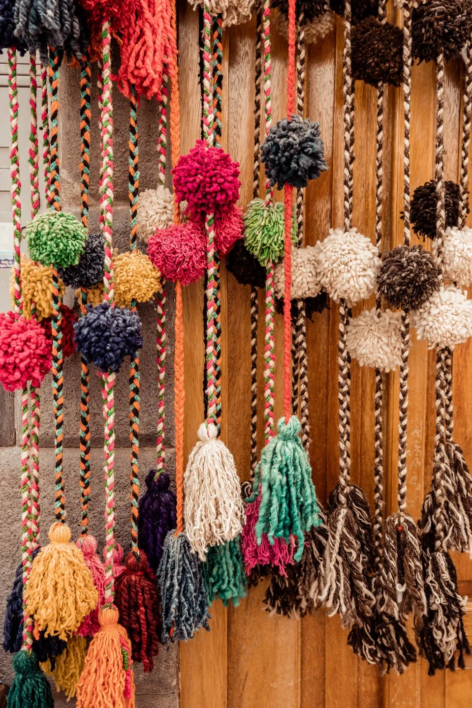 A bunch of different colored pom poms hanging on strings.